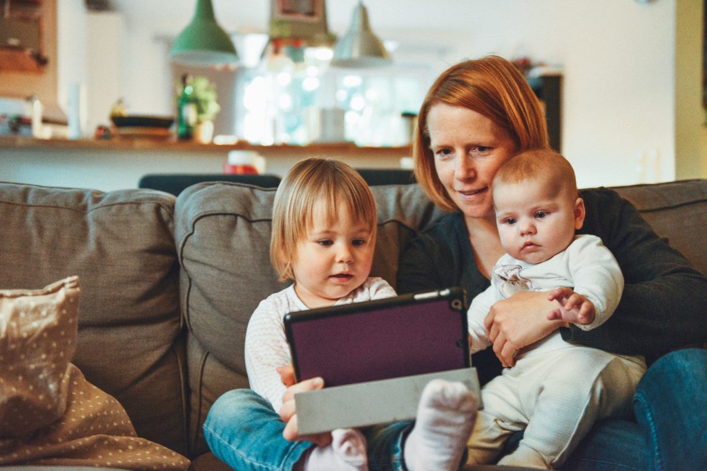 A mother reads to her two young children from a tablet, as they sit on a couch at Christmas. Reading the story of Jesus' arrival on Earth is a good way to reflect each year on this integral part of being a Christian.