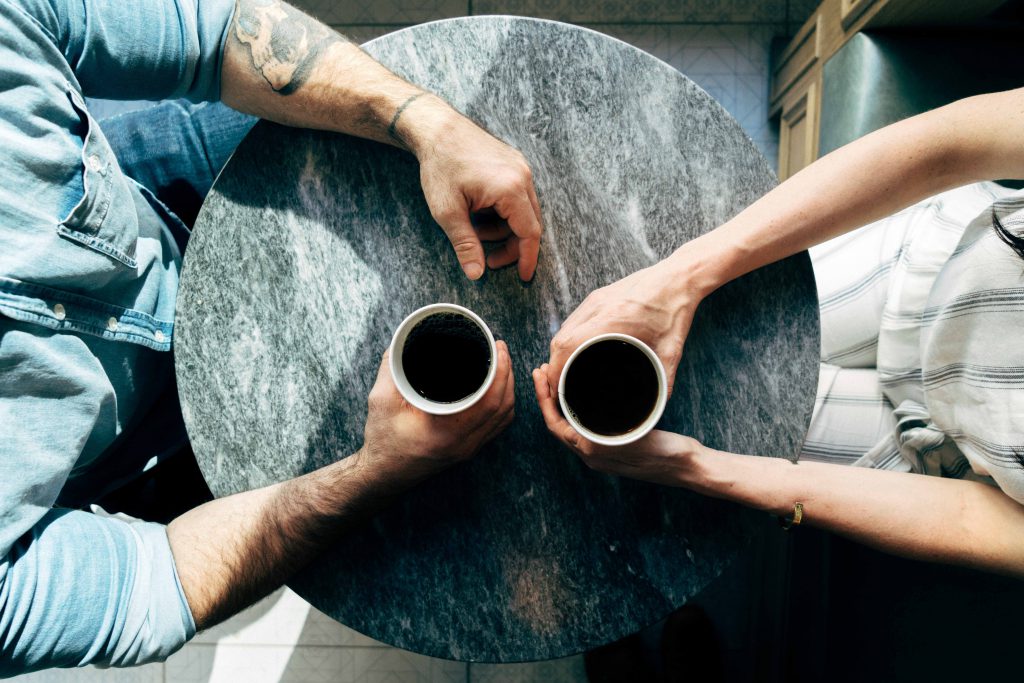 An older man and a younger woman meet for coffee and to talk about their spiritual lives, an example of mentorship.