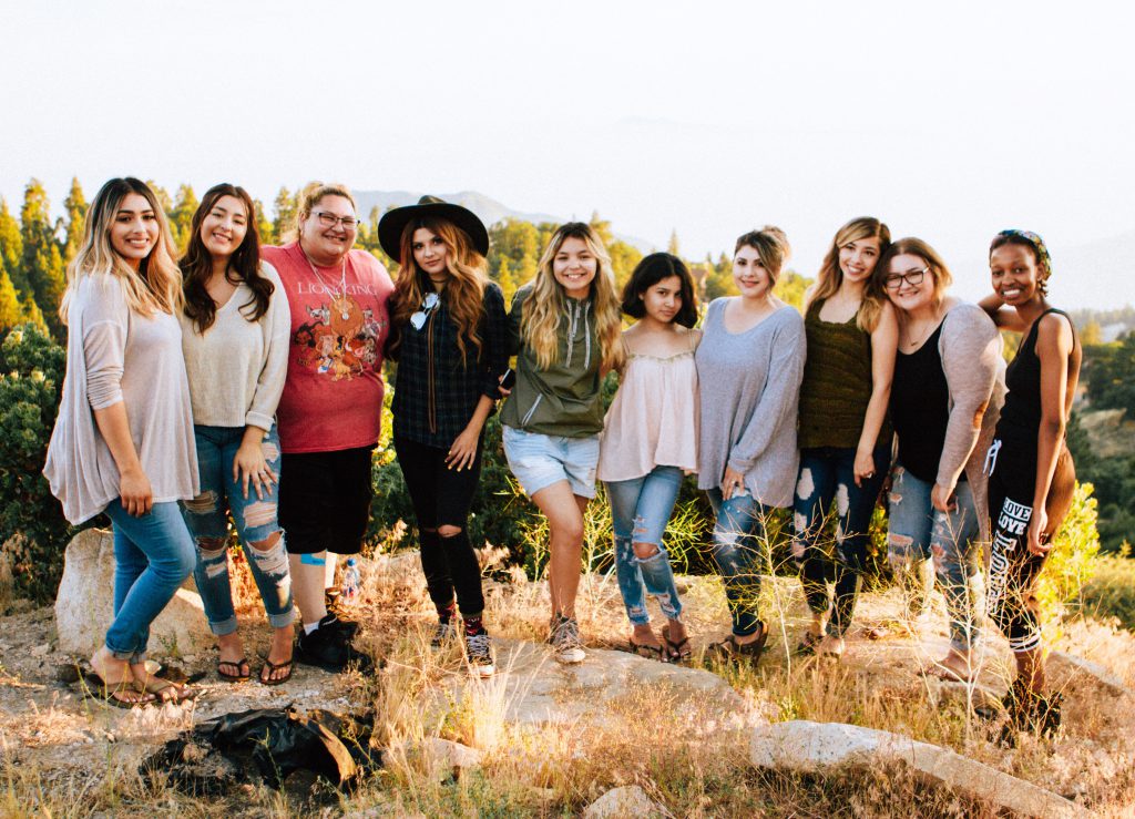 A group of 10 women stand and smile together taking a group picture. They make up an example of a strong small group.