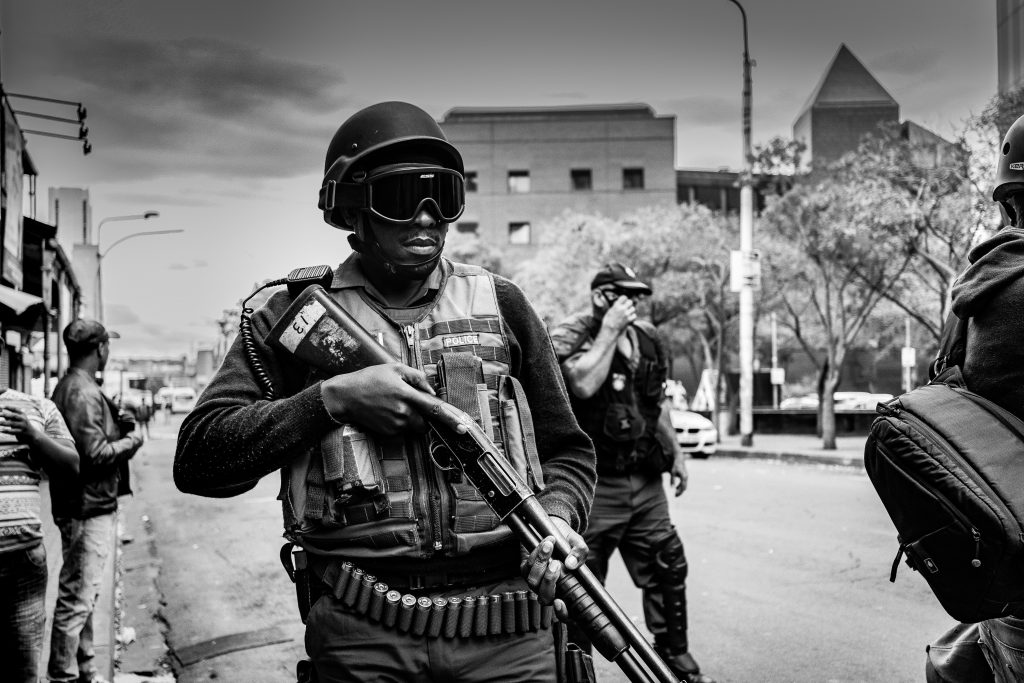 A soldier holds a shot gun in a war zone. Black and white image. Referring to the question, why does God allow evil and suffering in the world?