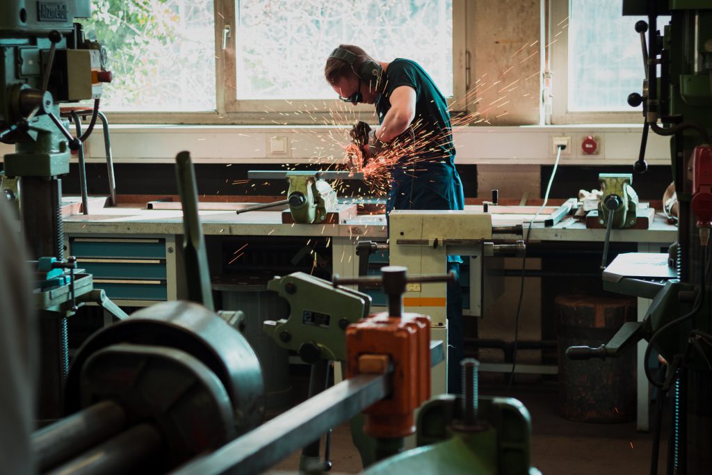 A man in goggles, ear defenders and an apron creates sparks that fly in his metal working shop. He is surrounded by tools and benches. We often just need to trust in God promises, relying on Him and demonstrating our faith in Him.